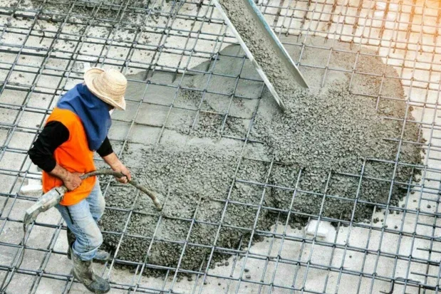 Worker directing concrete placement over a reinforcement grid