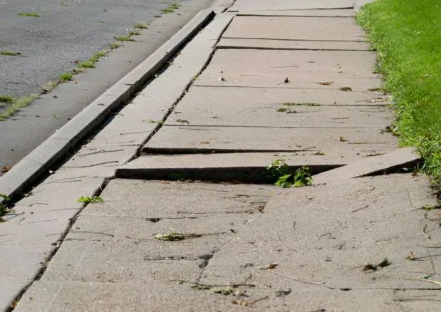 Damaged concrete sidewalk panels beside a curb